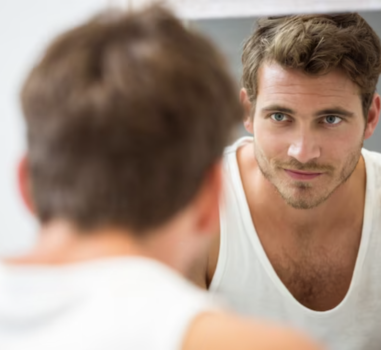 man with white shirt looking at his face